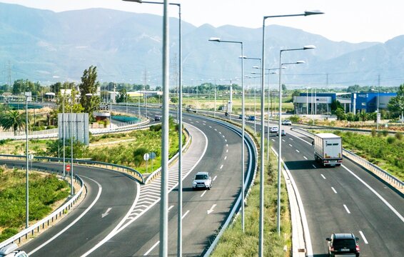 big highway of cars and street lapms,with mountains in the background, outside athens greece