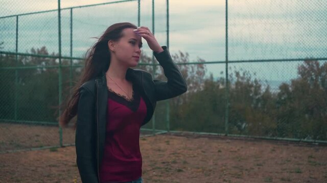 Beautiful hooligan girl with long hair and a leather jacket. Bad and cheeky girl. Hair blowing in the wind. Girl goes to the party. Video for advertising.