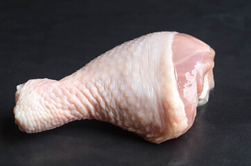 Close up of fresh rare chicken drumstick on  black stone  background.