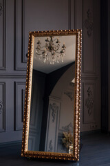 Luxurious gold floor mirror in dark interior