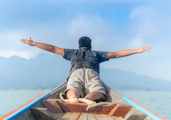 Foto op Canvas Asian traveler man laying and raising his hands in the air on boat,Freedom concept. © Patiwat