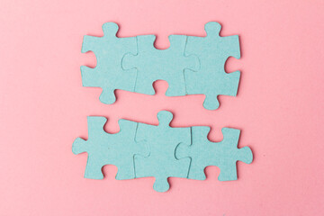 Blue puzzle pieces with empty space for your text and design on pink background.