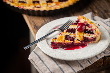 piece of Delicious homemade classic cherry pie with a flaky crust on dark rustic background