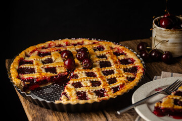 Delicious homemade classic cherry pie with a flaky crust on dark rustic background