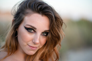 Naklejka premium Modelo pelirroja de maquillaje posa en la playa