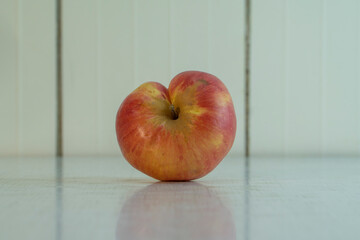 Misshapen Siamese twins apple on the white table in kitchen. Village fruit is good for healthy nutrition. it's contain many vitamins and microelements. Horizontal image with copy space.