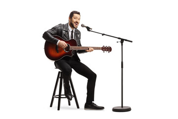 Fototapeta premium Man playing an acoustic guitar and singing on a microphone