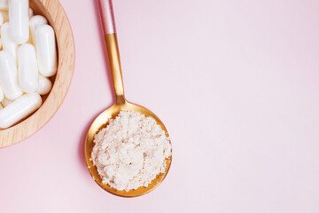 Collagen powder and pills on pink background