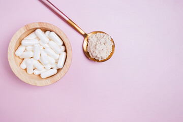 White pills and powder on pink background.