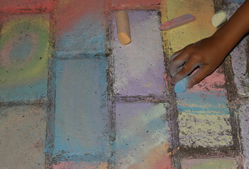 A child's hand holds Crayons. Drawings on the road. Children's entertainment.