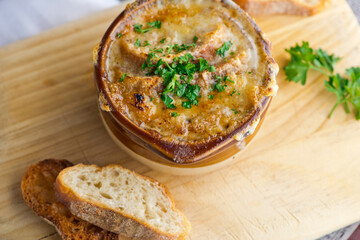 French Onion Soup. Classic traditional french restaurant bistro menu item. French onion soup, yellow onions reduced in broth topped with cheese melted and served with homemade baguettes. 
