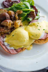 Eggs Benedict. Traditional classical American diner or French Bistro brunch item. Homemade Hollandaise sauce drizzled over a poached egg, country ham on top of a toasted English muffin with avocado.