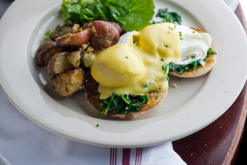 Eggs Benedict. Traditional classical American diner or French Bistro brunch item. Homemade Hollandaise sauce drizzled over a poached egg, country ham on top of a toasted English muffin with avocado.