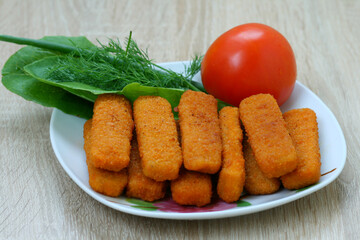 Delicious fried fish sticks with tomato and greens in a beautiful plate