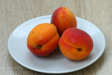 Three delicious apricots lying in a beautiful plate