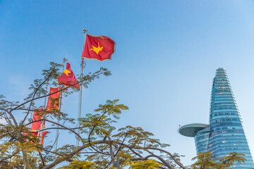 Bitexco tower under the blue sky next to a row of Vietnamese flags and the Vietnam Communist Party flags in Ho Chi Minh city, Vietnam