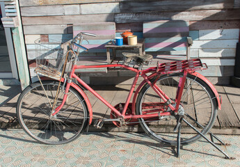 Fototapeta na wymiar Old red bicycle with wooden backdrop
