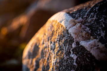 Stony beach stones and rocks sunlit in the evening closeup, texture sunset and sunrise
