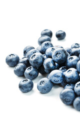 Tasty blueberries fruit are scattered on a white background.