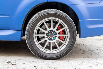 Stylish blue car wheel with red brake caliper and five-nut rim. Brake system support