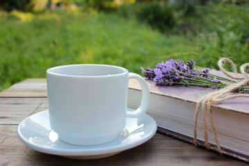 Cup of coffee and old book decorated with lavender flowers and tied with jute twine on wooden table. Copy space. Selective focus. Enjoying summer life
