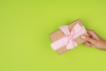 Top view of female hands holding a present box package in palms, on green background