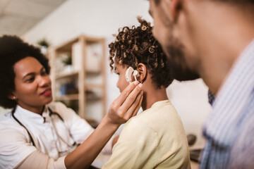 Smiling deaf african american girl with ear implant at doctor's office.