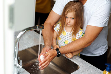 Father and daughter washing their hands above the sink in a kitchen