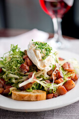 Salad. Frisee lettuce dress with olive oil and balsamic vinegar and topped with bacon lardons a fried egg and garnished with italian parsely and a toasted baguette. Served in a French Bistro.