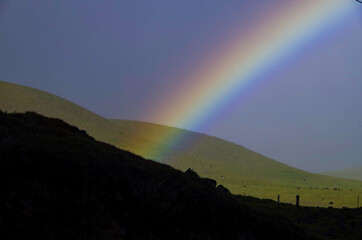 Rainbow over Kohala mountain summit with silhouette and shadow of hills