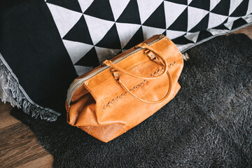Naklejka premium Leather travel bag near the bed in the living room. travel preparation, weekend concept.