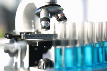 Close up of laboratory glass microscope near medical test tubes in holder. Chemistry and biology concept