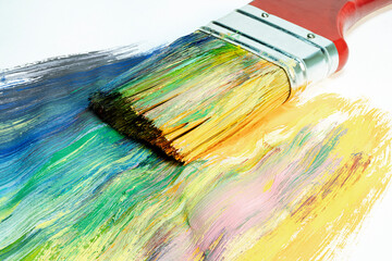 Obraz premium A large wooden art brush paints on canvas. Drawing technique. Bright colors on the canvas. Hobbies and creativity. Painting