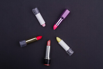 Set of different lipstick isolated equalled a circle on black background. Beautiful Make-up concept. Red pink yellow lipsticks.