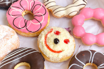 smiling face donut  amidst Colorful donuts on white background,Different thinking, positive thinking concept.