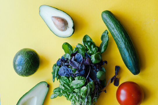 Fresh lettuce, avocado in a small pot. Green leaves on a yellow background. Flat lay. Eco food. Place for text