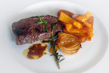 ready to eat - roasted venison from the chamois buck with onions, orange paprika and rosemary on a white plate