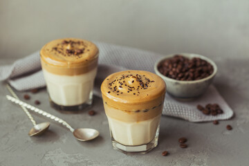Glass of Iced Dalgona Coffee, trendy fluffy creamy whipped coffee and milk on grey background.