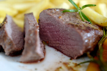 ready to eat - roasted venison from the chamois buck with vegetables and french fries on a white plate