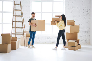 Young couple in love unpacking cardboard boxes just moved to rent apartment making...