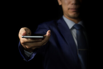 Businessman showing mobile phone on hand with black background