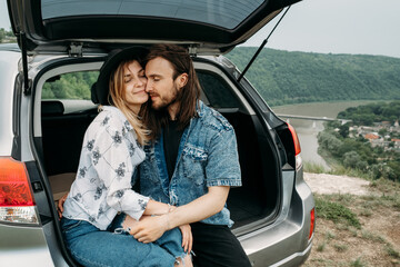 Young Stylish Traveling Hipsters Having Fun Sitting in Car Trunk Near the River Canyon, Travel and Road Trip Concept