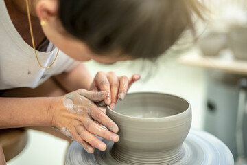 Fototapeta na wymiar junge Frau dreht eine Schale aus feuchter Keramik an der elektrischen Drehscheibe 