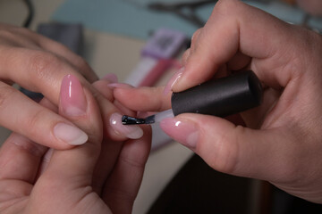 the process of doing manicure. Closeup of hands of professional manicurist, applying nail polish. Concept of doing manicure and fingernails cleaning. beauty concept. Gel polish, shellac