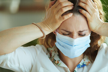 stressed young woman in white blouse with medical mask