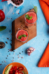  classic spanish raw eating cold soup Gazpacho served  in glasses around blue background. food recipe. healthy concept.