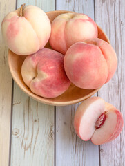 Fresh organic peach or apricot in wood bowl on wood background.