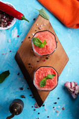 classic spanish raw eating cold soup Gazpacho served  in glasses around blue background. food recipe. healthy concept.