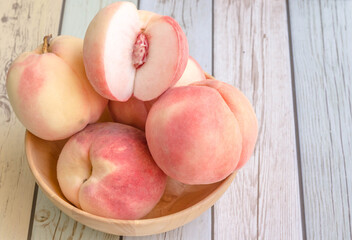 Fresh organic peach or apricot in wood bowl on wood background.