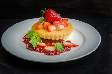Homemade cheese cakes served with strawberry sauce made from organic strawberries. Topping with fresh organic strawberries and decorated with mint leaves.